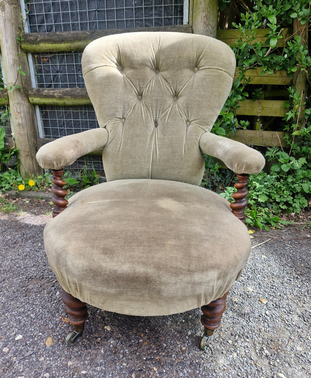 A mid-Victorian armchair upholstered in sage green velvet featuring a deep buttoned backrest, padded arms on barley twist supports, and turned legs with castors. View VI