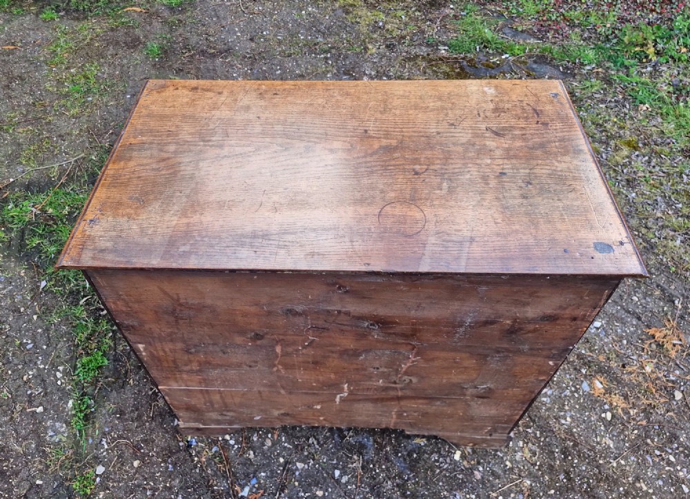 An early nineteenth-century oak chest of drawers featuring two short drawers above three long drawers with brass drop handles and a moulded top edge. View III