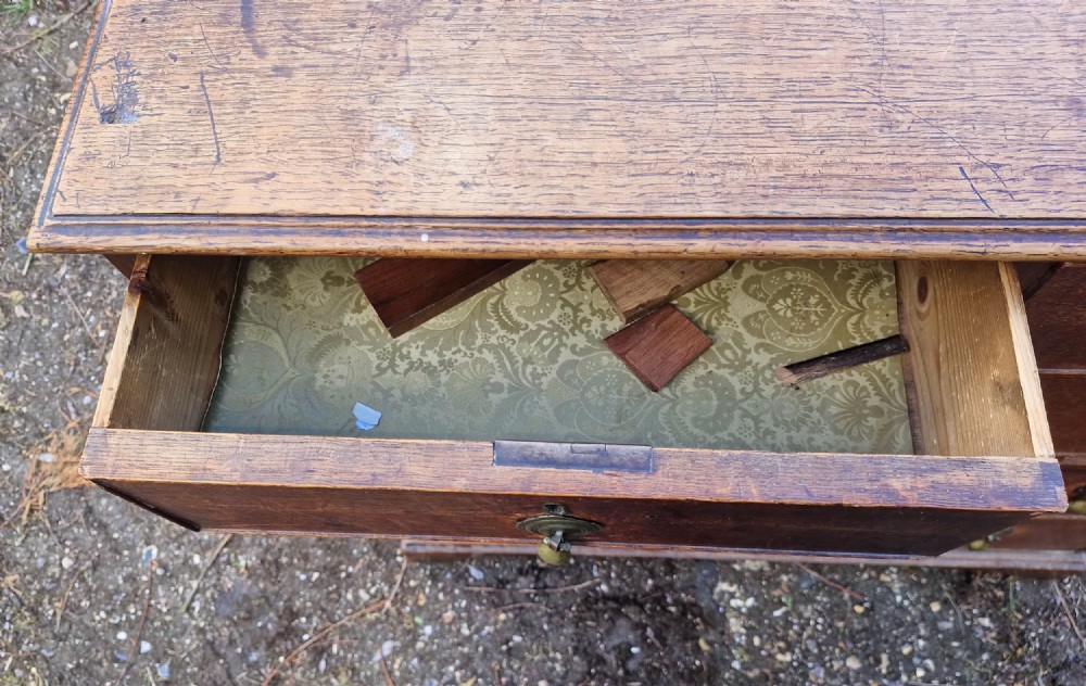 An early nineteenth-century oak chest of drawers featuring two short drawers above three long drawers with brass drop handles and a moulded top edge. View IV