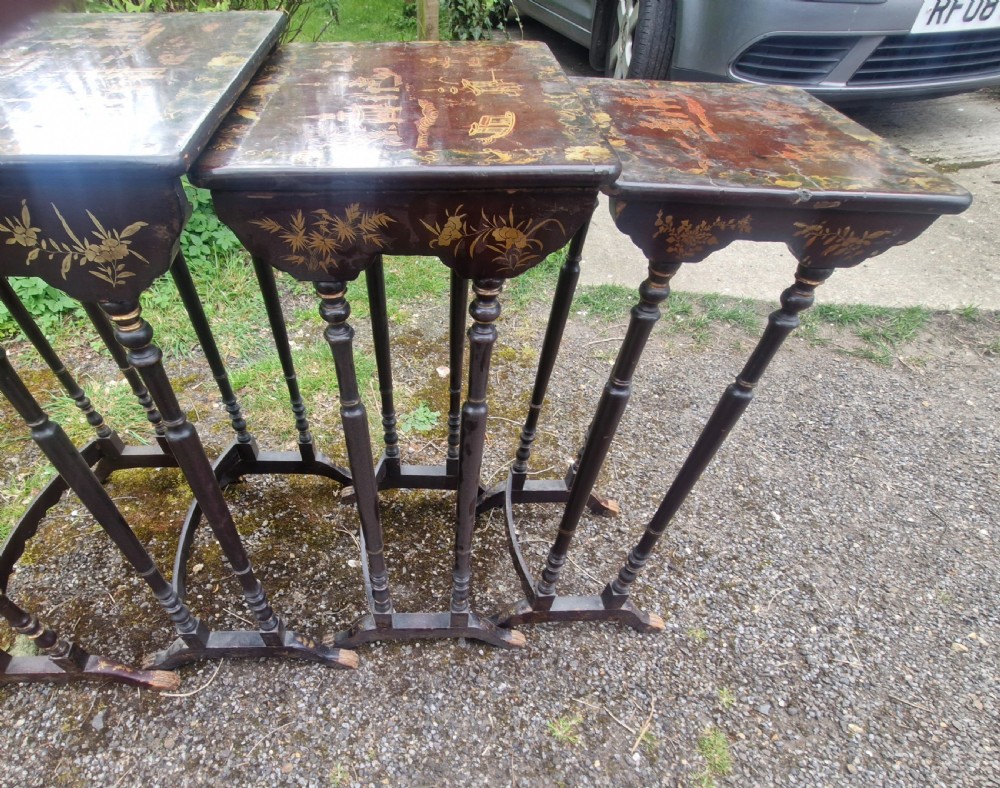 A set of four dark brown lacquered nesting tables decorated with hand-painted gilt chinoiserie landscape scenes and slender turned legs. View II
