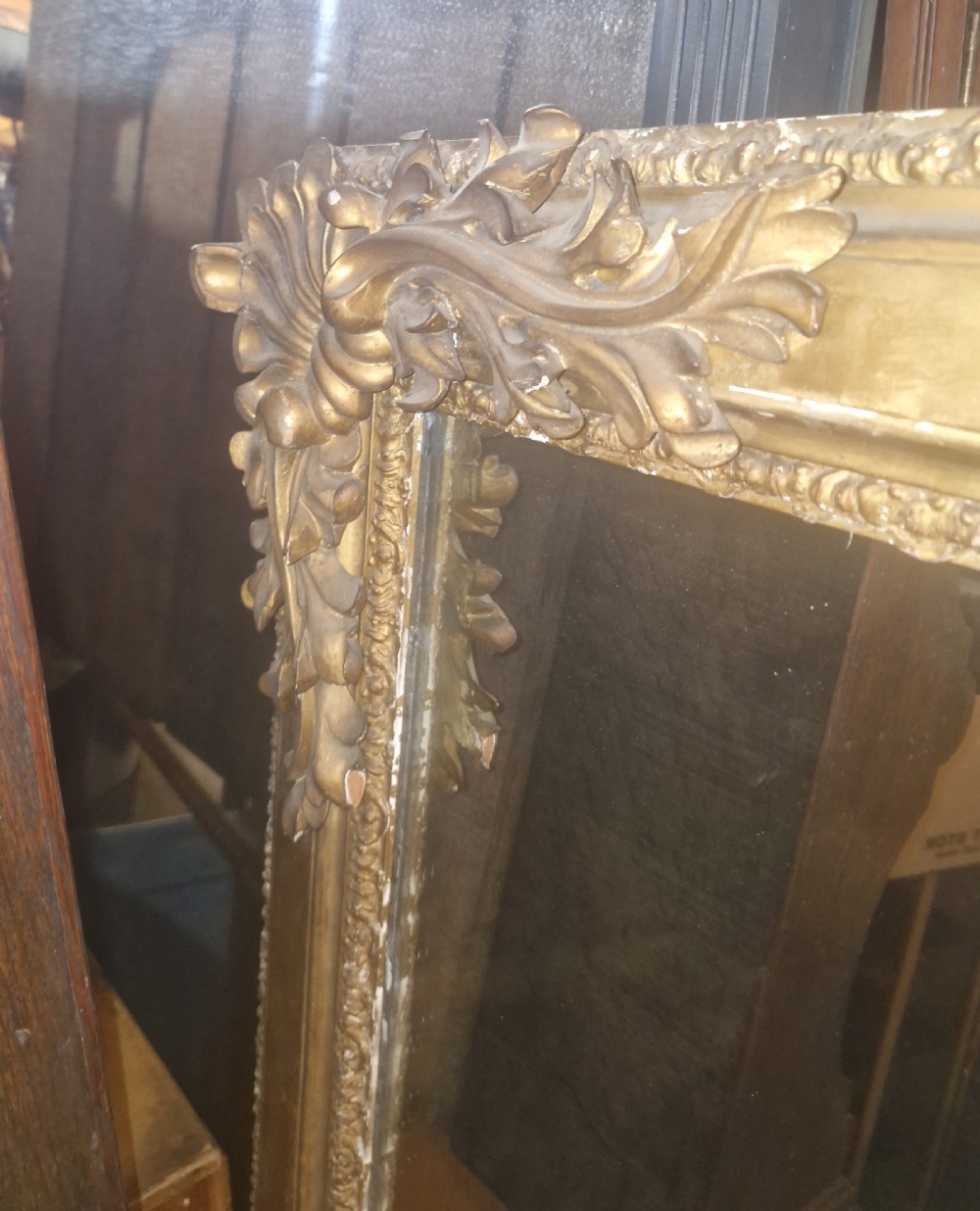A large rectangular 19th-century overmantel mirror featuring a gilded wood frame with carved acanthus leaves at the top corners and bead moulding along the inner border. View X