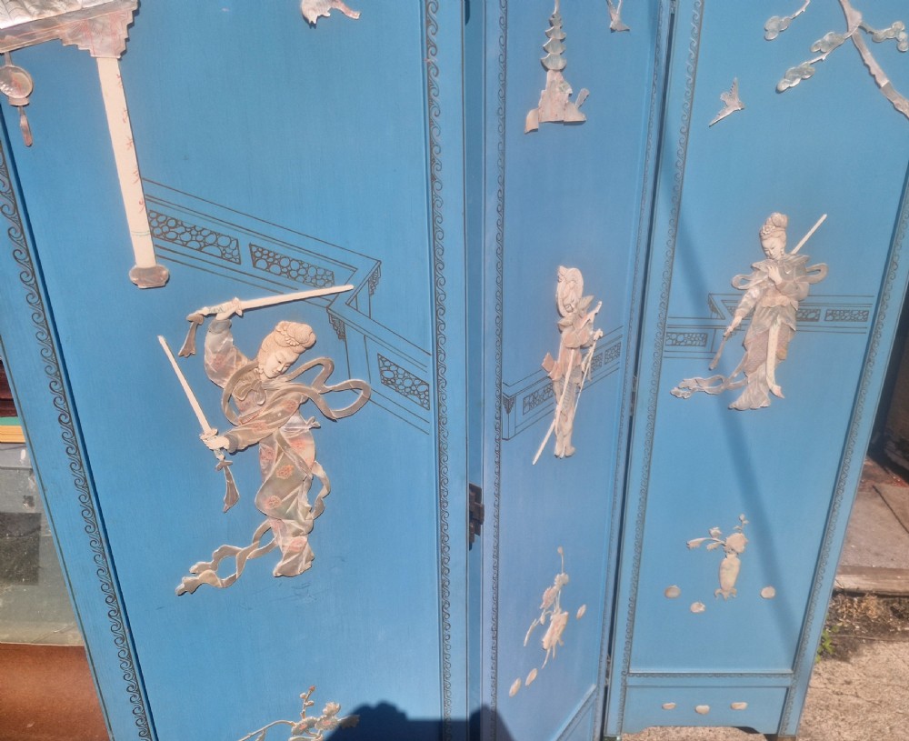 A painted blue three-panel folding screen decorated with mother-of-pearl inlaid figures, pagodas, birds, and botanical motifs. View III