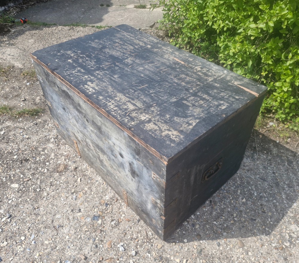 A rectangular antique dark-painted wooden campaign trunk with iron corner brackets and side carrying handles. View V