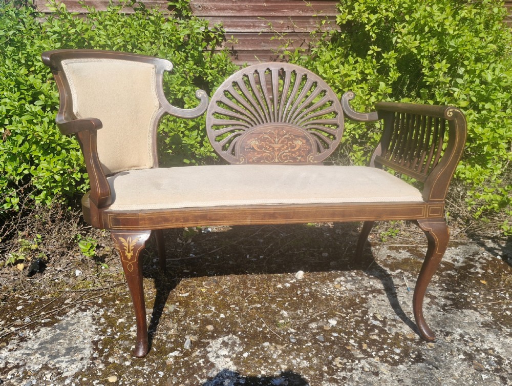 An Edwardian inlaid mahogany window seat with cream upholstery, a central carved fan splat, and scrolled arms. View II