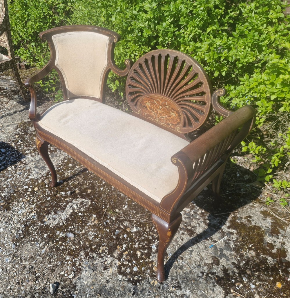 An Edwardian inlaid mahogany window seat with cream upholstery, a central carved fan splat, and scrolled arms. View III