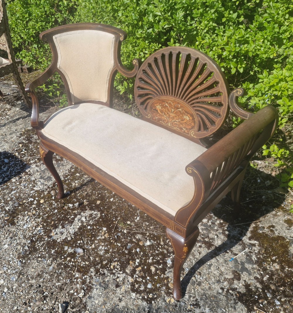 An Edwardian inlaid mahogany window seat with cream upholstery, a central carved fan splat, and scrolled arms. View VI