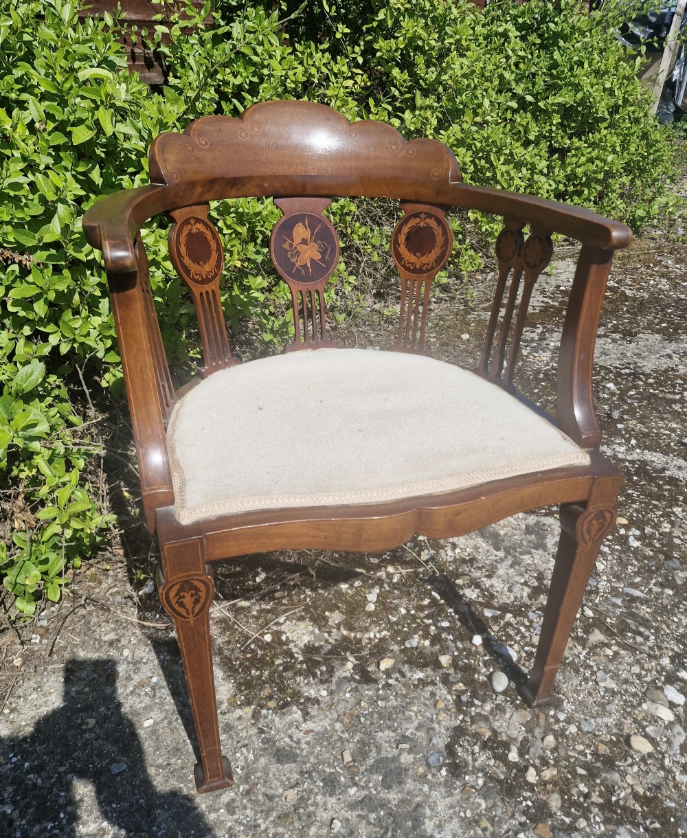 An Edwardian mahogany tub armchair featuring decorative marquetry inlay on the splats and front legs, curved armrests, and a light upholstered seat. View IV
