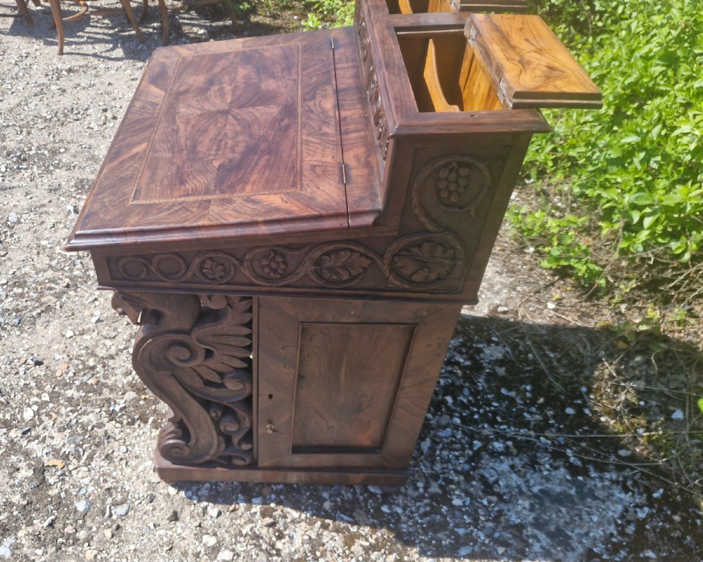 An antique carved olivewood Davenport writing desk with a sloped lid, foliage carvings, and decorative scrolled supports. View VII