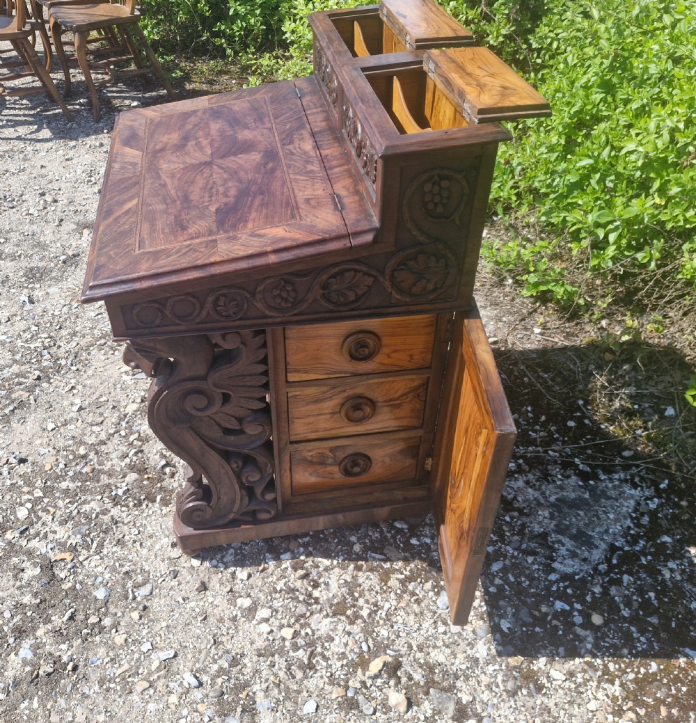 An antique carved olivewood Davenport writing desk with a sloped lid, foliage carvings, and decorative scrolled supports. View XI