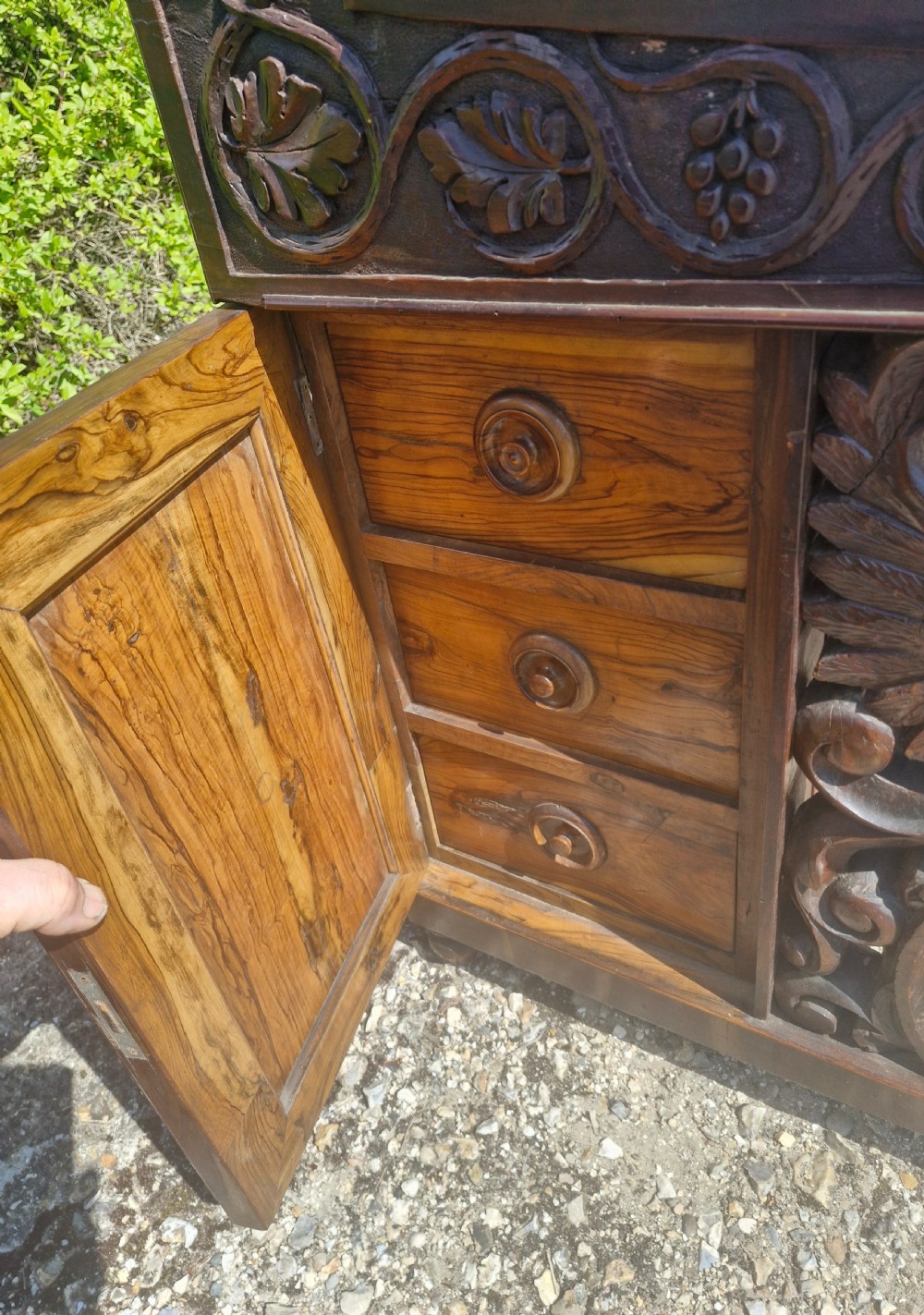 An antique carved olivewood Davenport writing desk with a sloped lid, foliage carvings, and decorative scrolled supports. View XV