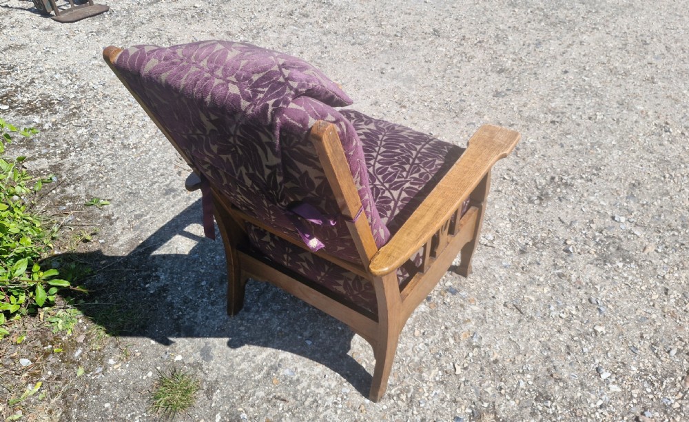 An Arts and Crafts oak reclining armchair with patterned purple upholstery and pierced side splats. View II