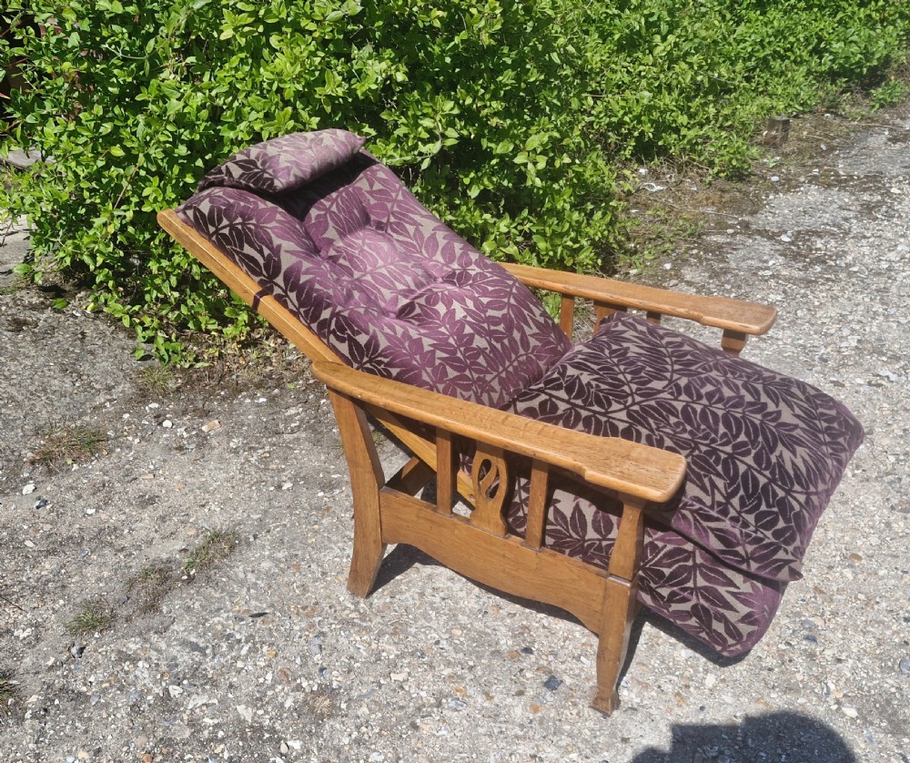 An Arts and Crafts oak reclining armchair with patterned purple upholstery and pierced side splats. View III