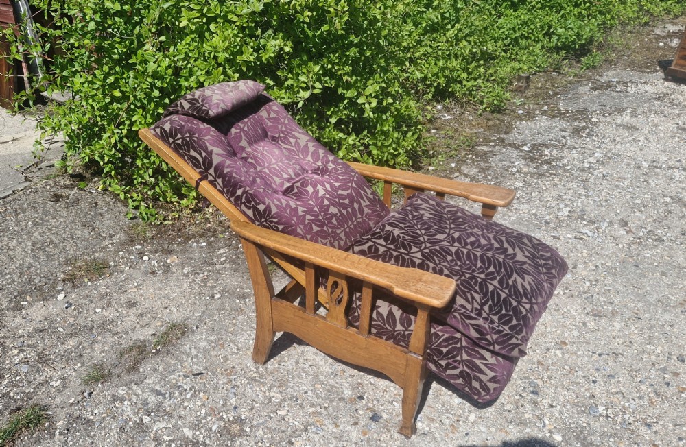 An Arts and Crafts oak reclining armchair with patterned purple upholstery and pierced side splats. View IV