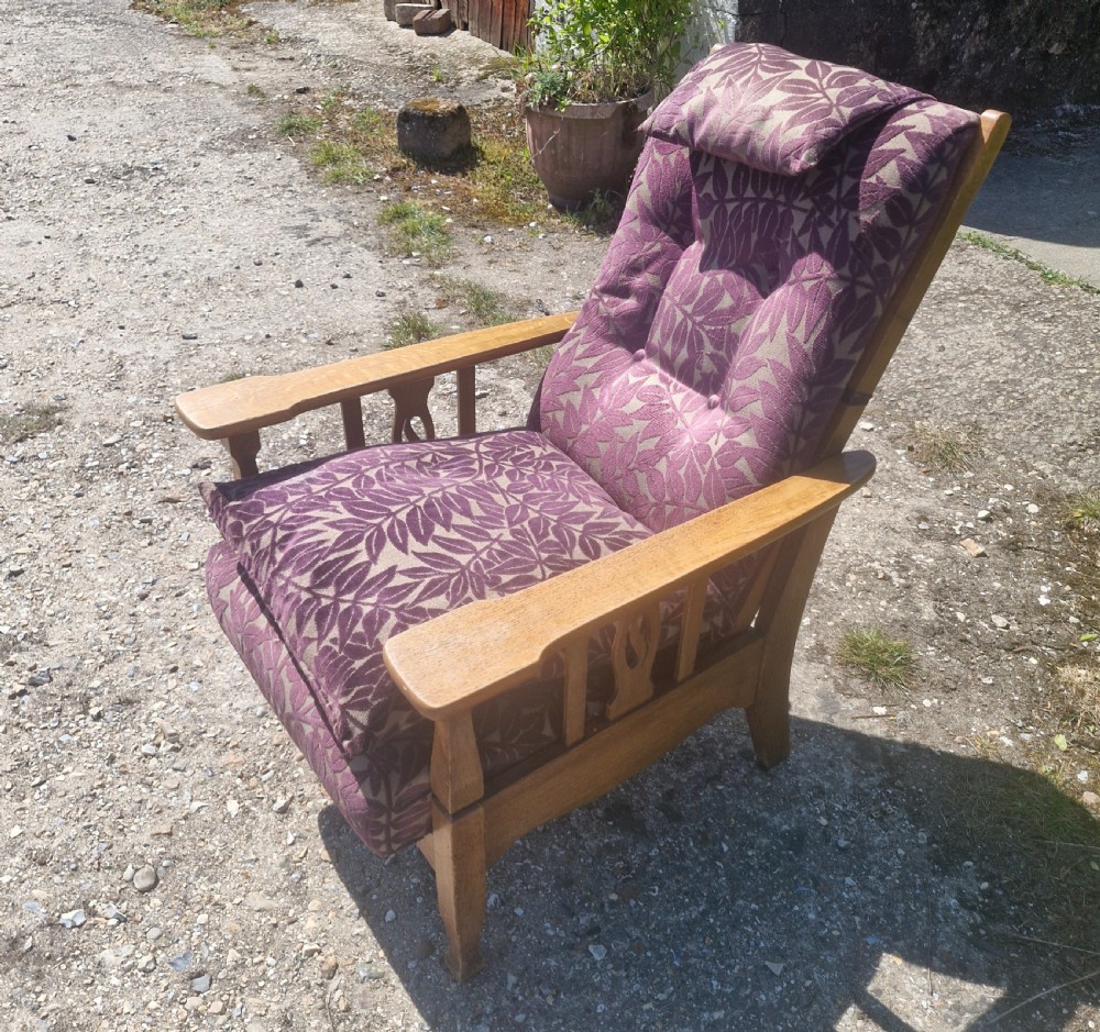 An Arts and Crafts oak reclining armchair with patterned purple upholstery and pierced side splats. View V