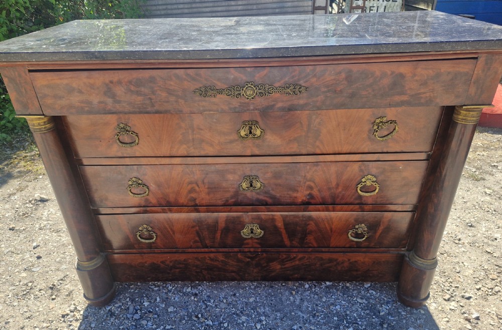 A nineteenth-century French mahogany chest of drawers featuring a dark grey marble top, four drawers with brass drop handles, and flanking side columns. View II