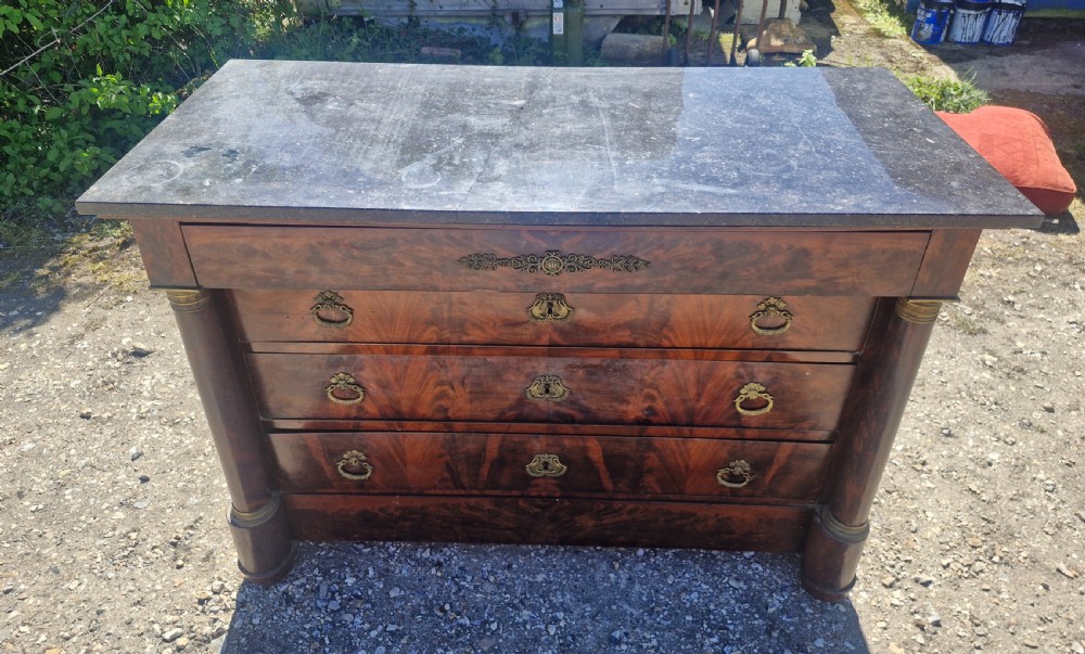 A nineteenth-century French mahogany chest of drawers featuring a dark grey marble top, four drawers with brass drop handles, and flanking side columns. View VIII