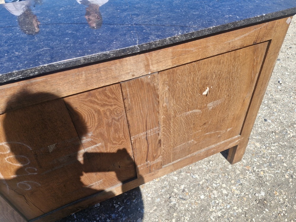 A nineteenth-century French mahogany chest of drawers featuring a dark grey marble top, four drawers with brass drop handles, and flanking side columns. View X