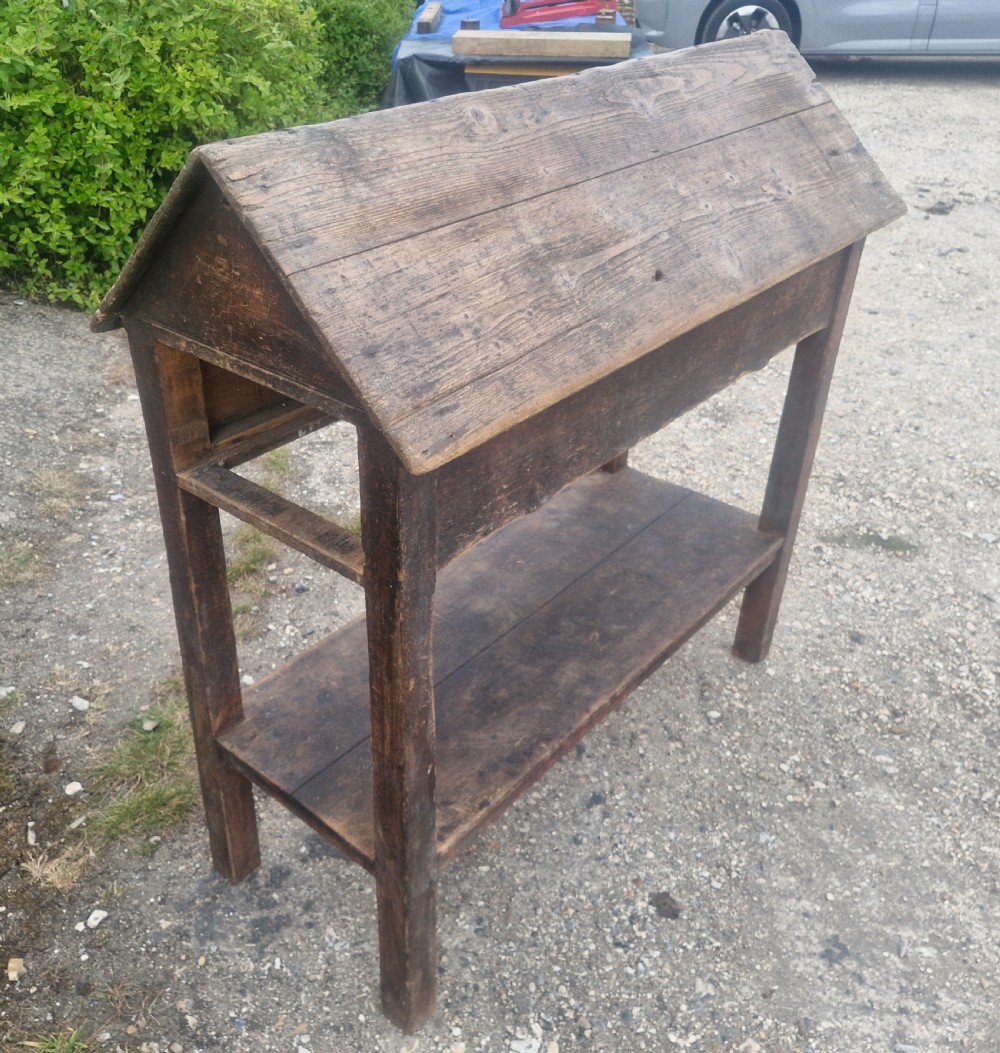 A freestanding Victorian weathered pine saddle rack featuring a pitched A-frame top, a single side drawer with a turned wooden knob, and a lower open shelf. View II