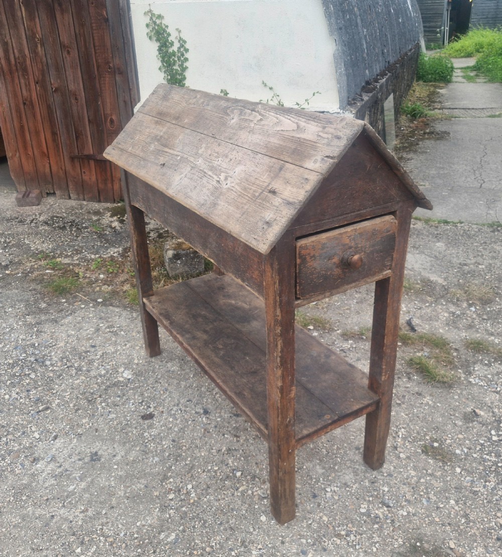 A freestanding Victorian weathered pine saddle rack featuring a pitched A-frame top, a single side drawer with a turned wooden knob, and a lower open shelf. View III
