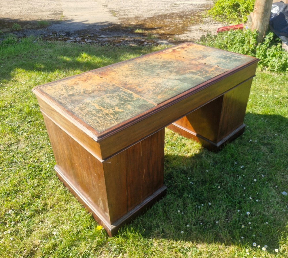 A late Victorian mahogany kneehole desk featuring twin pedestals with drawers, a plinth base, and a worn leather writing surface. View II