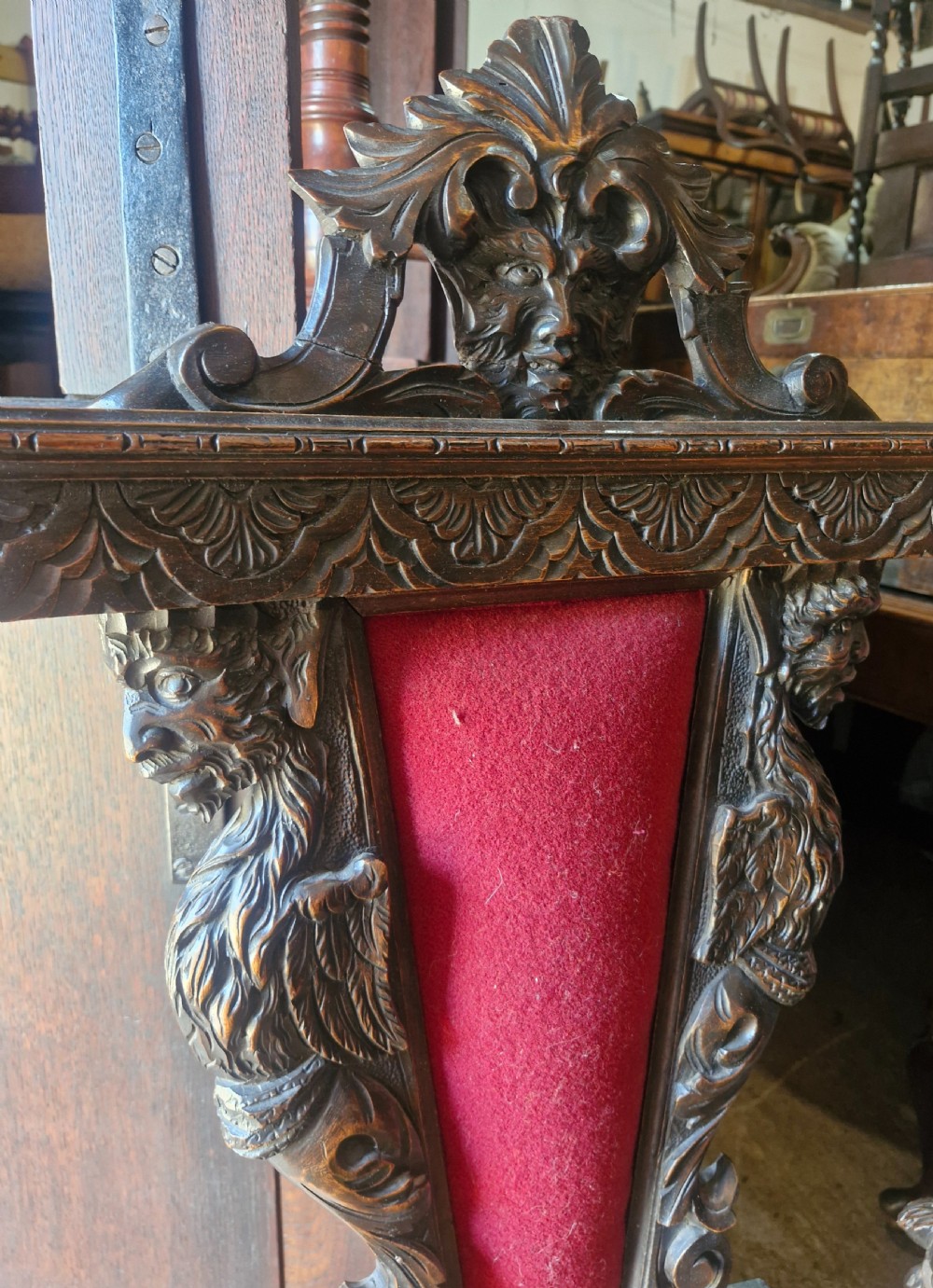 A pair of 19th-century carved walnut hall chairs featuring relief mascarons, scrollwork legs, and red velvet backrest panels. View III