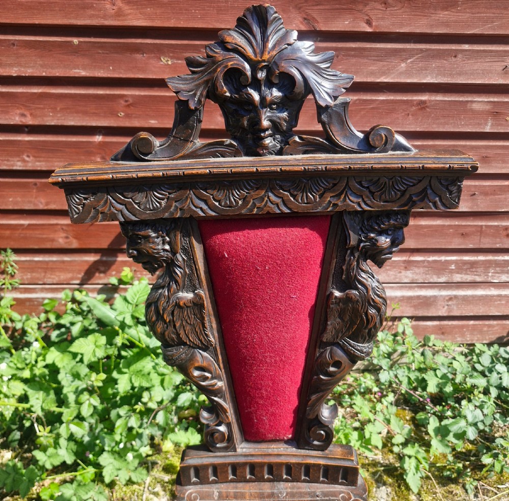 A pair of 19th-century carved walnut hall chairs featuring relief mascarons, scrollwork legs, and red velvet backrest panels. View IV