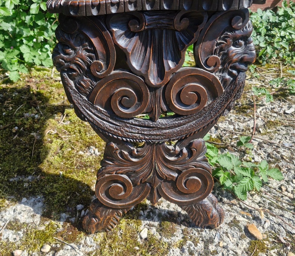 A pair of 19th-century carved walnut hall chairs featuring relief mascarons, scrollwork legs, and red velvet backrest panels. View VII