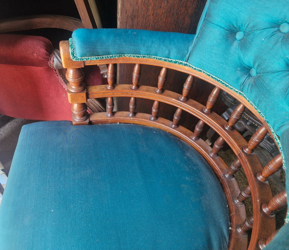 A Victorian wooden desk armchair featuring teal blue button-backed upholstery, a curved spindle gallery, and turned legs. View II