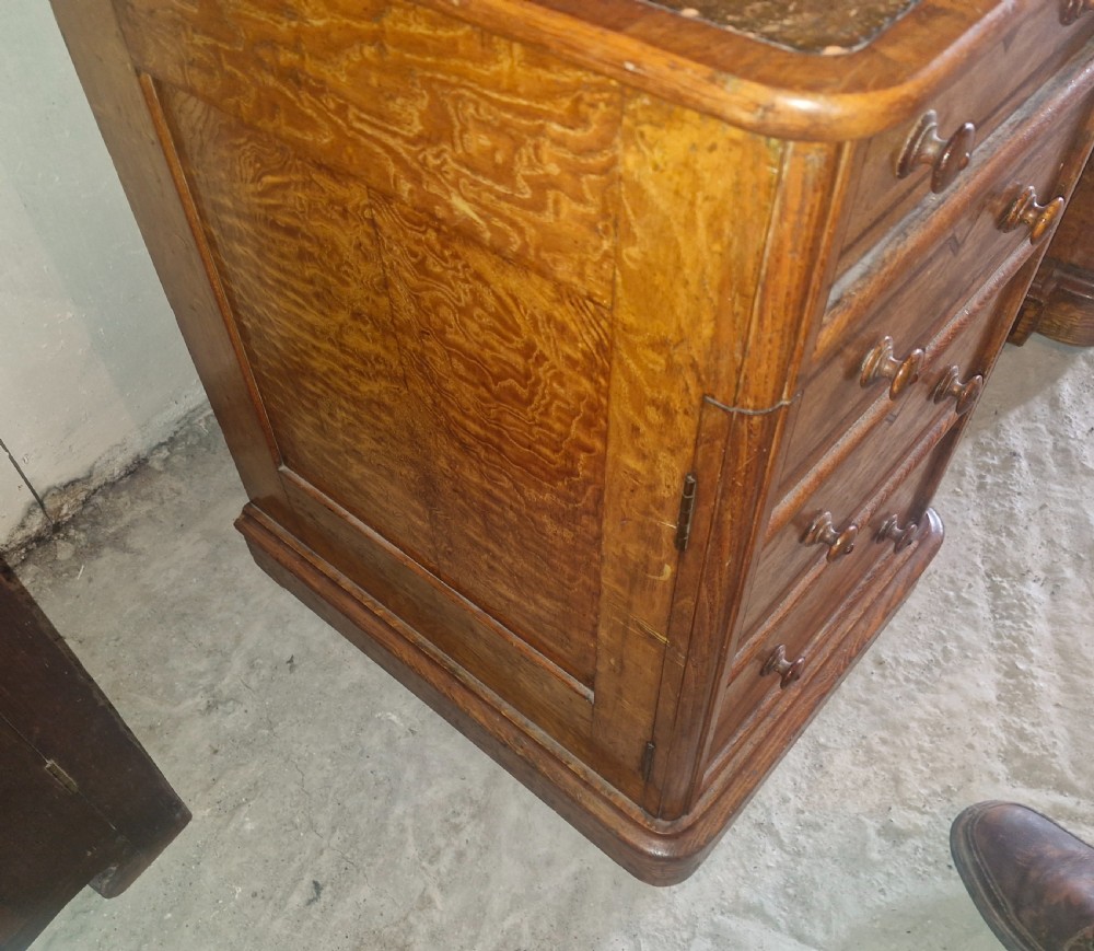 A Victorian Hungarian ash pedestal writing desk featuring a worn leather top, turned wooden drawer knobs, and inlaid geometric crossbanding. View III