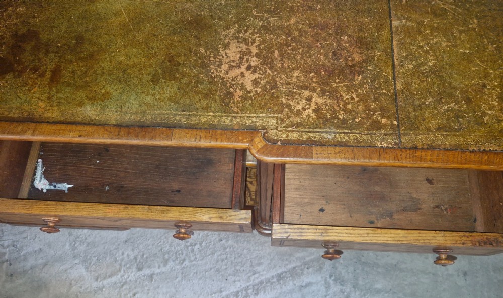 A Victorian Hungarian ash pedestal writing desk featuring a worn leather top, turned wooden drawer knobs, and inlaid geometric crossbanding. View VII