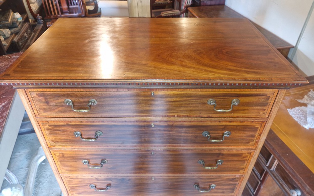 An Edwardian mahogany chest of six drawers featuring satinwood inlay banding, brass drop handles, and bracket feet. View IV