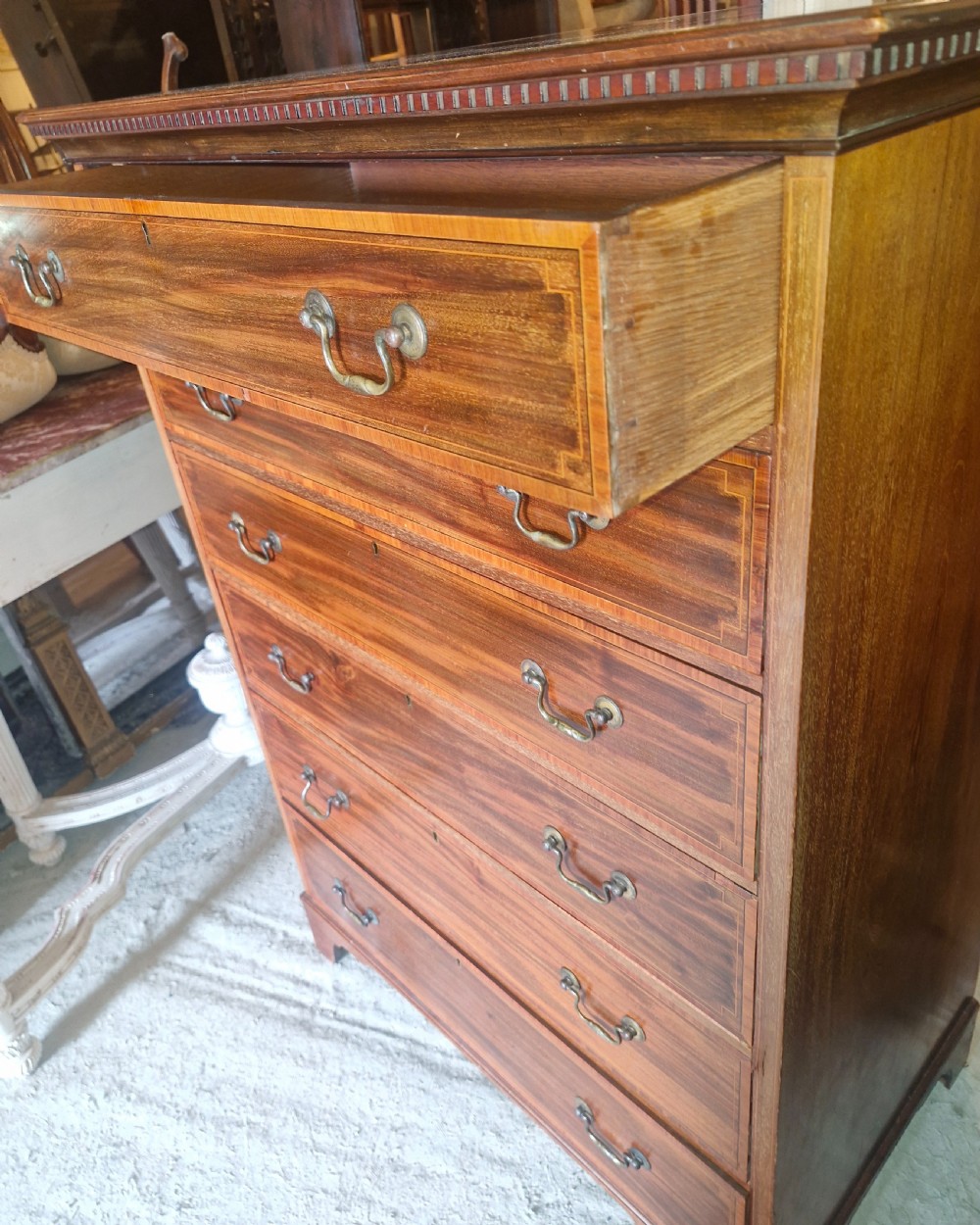 An Edwardian mahogany chest of six drawers featuring satinwood inlay banding, brass drop handles, and bracket feet. View V