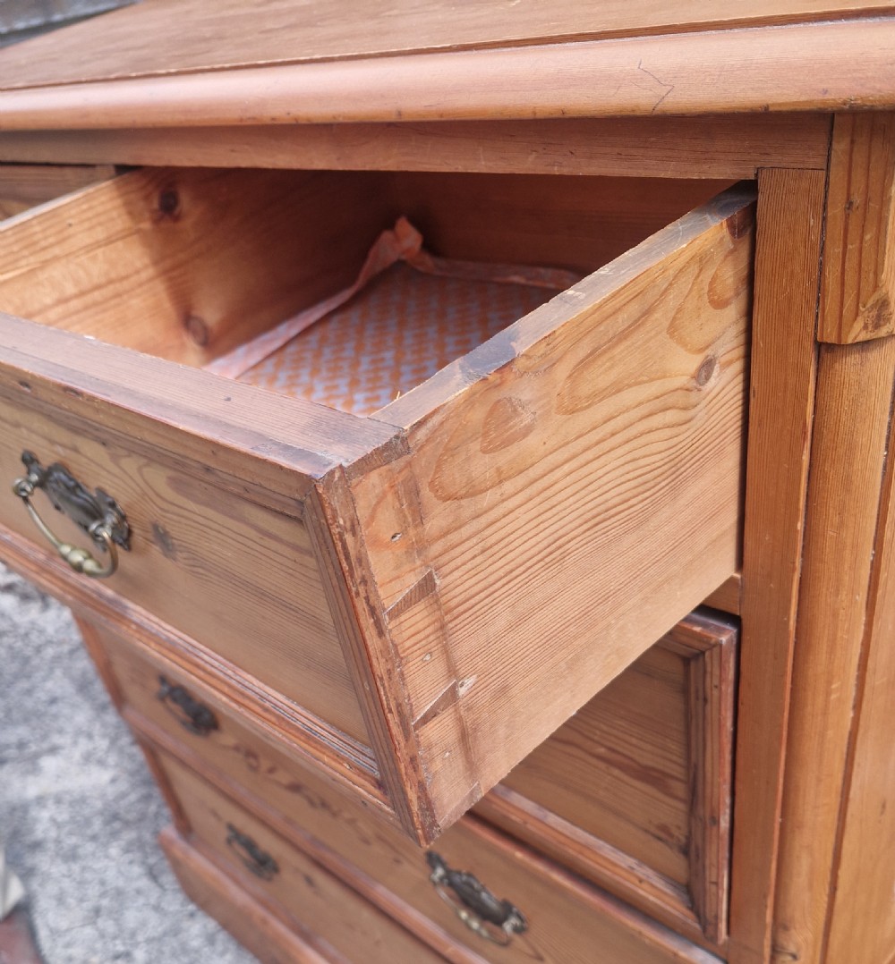 An Edwardian pine chest of drawers featuring a two-over-three drawer configuration with brass drop handles and a plinth base. View II