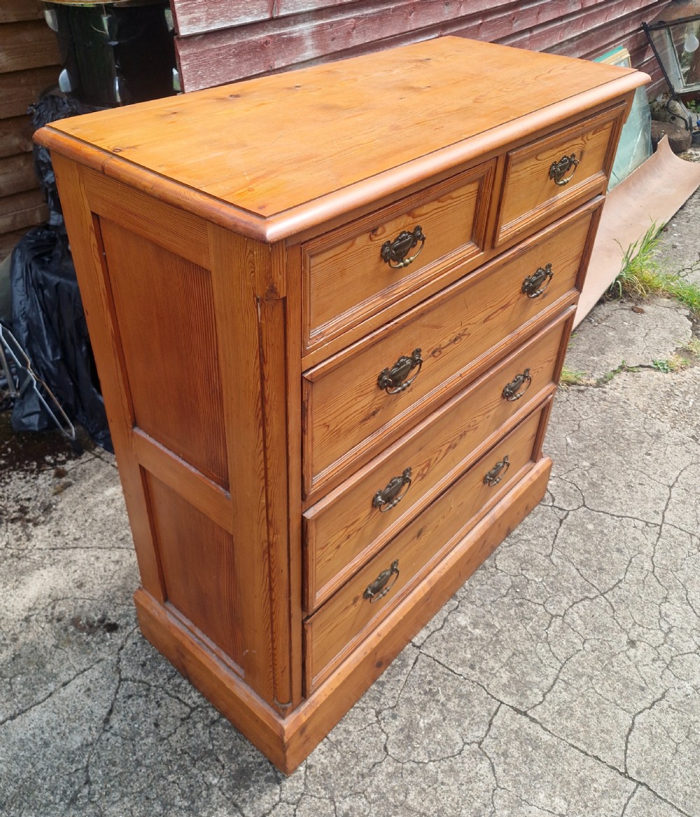 An Edwardian pine chest of drawers featuring a two-over-three drawer configuration with brass drop handles and a plinth base. View IV