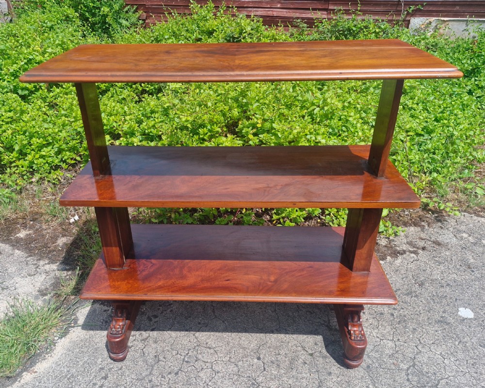 A three-tiered Victorian walnut adjustable buffet with carved lower supports resting outdoors on paved ground.