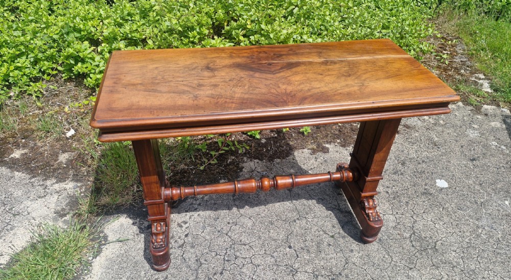 A three-tiered Victorian walnut adjustable buffet with carved lower supports resting outdoors on paved ground. View II
