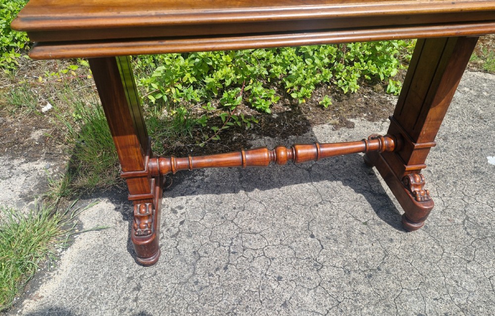 A three-tiered Victorian walnut adjustable buffet with carved lower supports resting outdoors on paved ground. View III