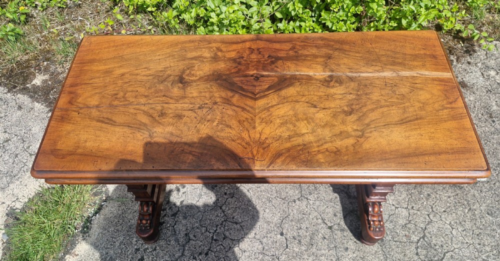 A three-tiered Victorian walnut adjustable buffet with carved lower supports resting outdoors on paved ground. View V