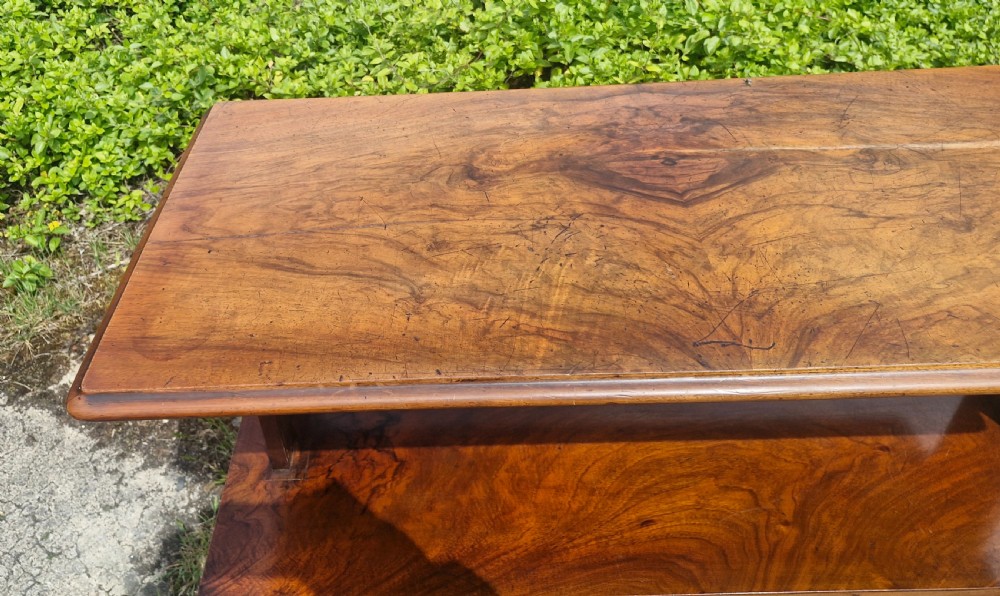 A three-tiered Victorian walnut adjustable buffet with carved lower supports resting outdoors on paved ground. View VI