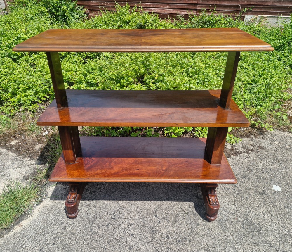 A three-tiered Victorian walnut adjustable buffet with carved lower supports resting outdoors on paved ground. View VII