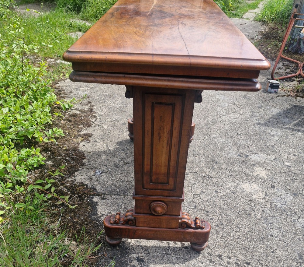 A three-tiered Victorian walnut adjustable buffet with carved lower supports resting outdoors on paved ground. View XI