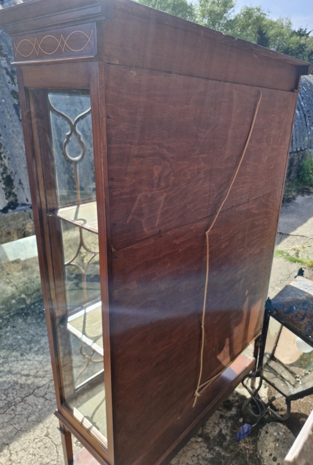 An Edwardian mahogany display cabinet featuring astragal glazed doors, geometric satinwood inlay, a curved central glass section, and a lower undertier. View II
