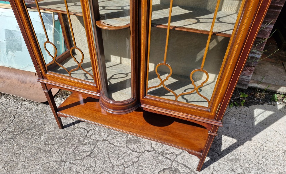 An Edwardian mahogany display cabinet featuring astragal glazed doors, geometric satinwood inlay, a curved central glass section, and a lower undertier. View III