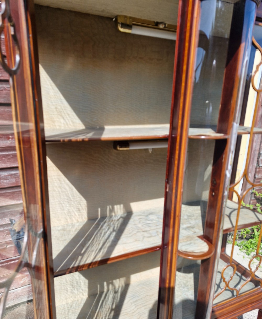 An Edwardian mahogany display cabinet featuring astragal glazed doors, geometric satinwood inlay, a curved central glass section, and a lower undertier. View V