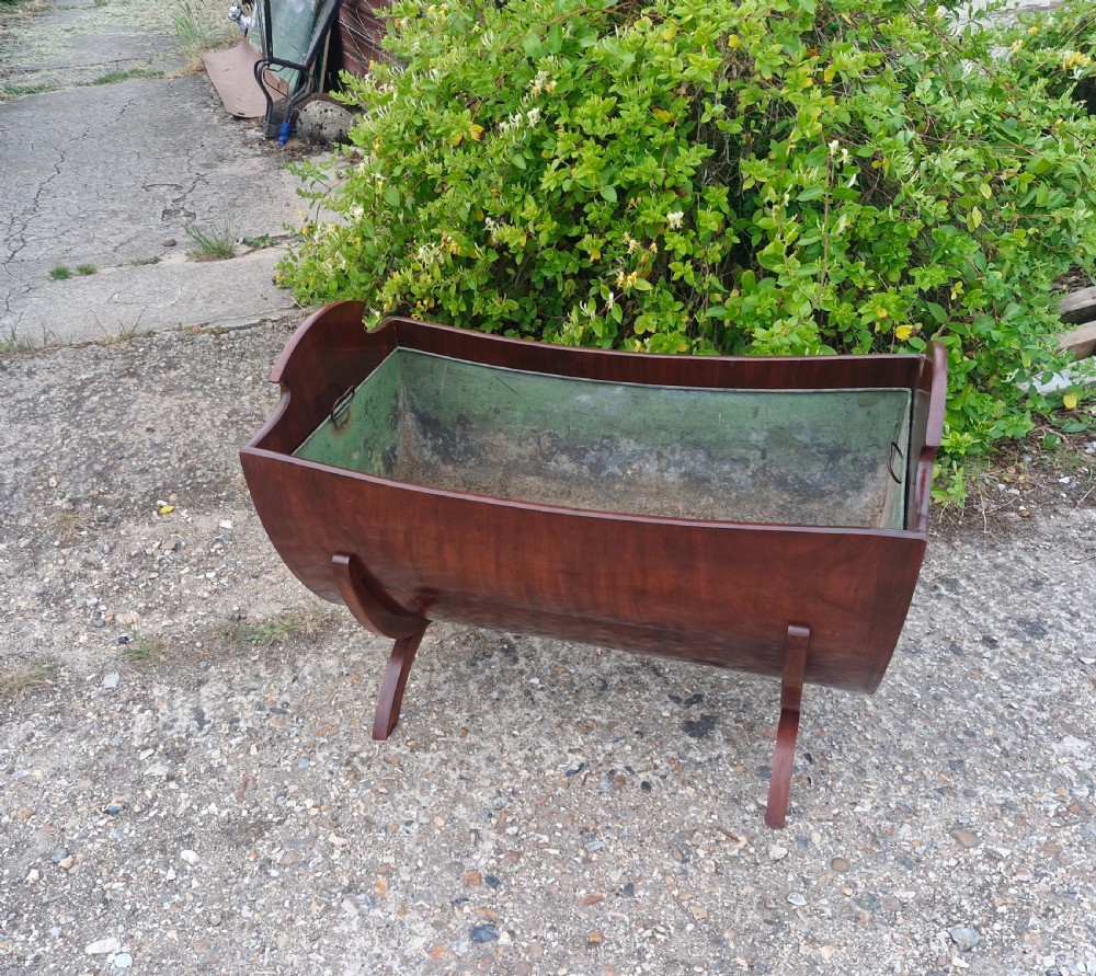 A 19th-century mahogany trough-shaped wine cooler or log bin with a removable green metal liner on splayed legs.