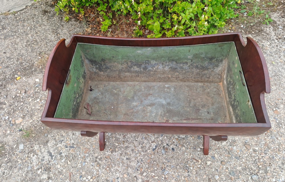 A 19th-century mahogany trough-shaped wine cooler or log bin with a removable green metal liner on splayed legs. View V