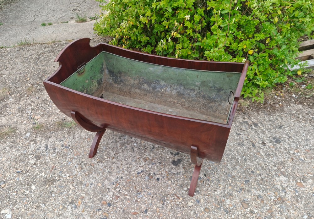 A 19th-century mahogany trough-shaped wine cooler or log bin with a removable green metal liner on splayed legs. View VI