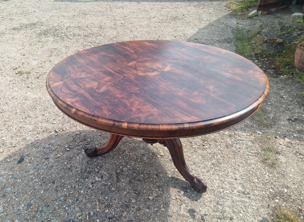 A mid-19th-century circular rosewood centre table shown tilted vertically to display its symmetrical figured grain and carved pedestal base. View III