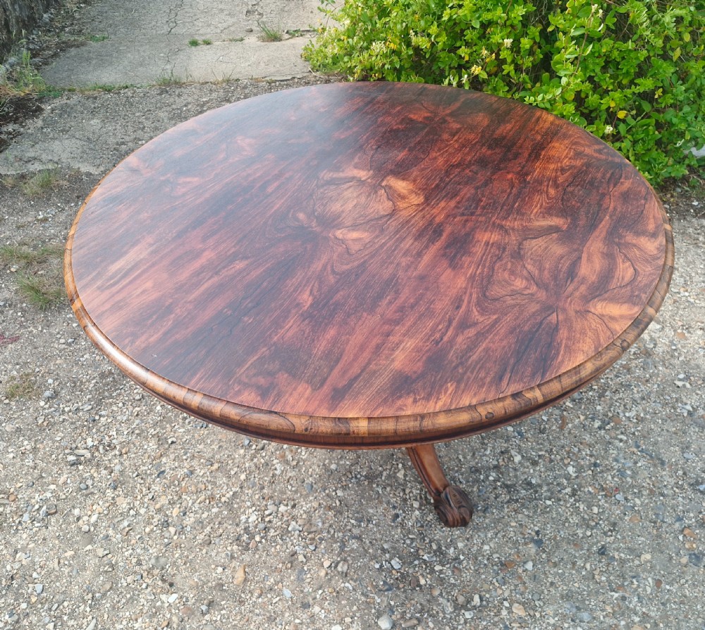 A mid-19th-century circular rosewood centre table shown tilted vertically to display its symmetrical figured grain and carved pedestal base. View IV