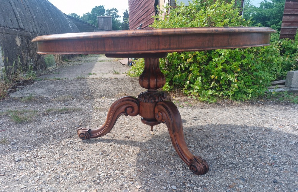 A mid-19th-century circular rosewood centre table shown tilted vertically to display its symmetrical figured grain and carved pedestal base. View V